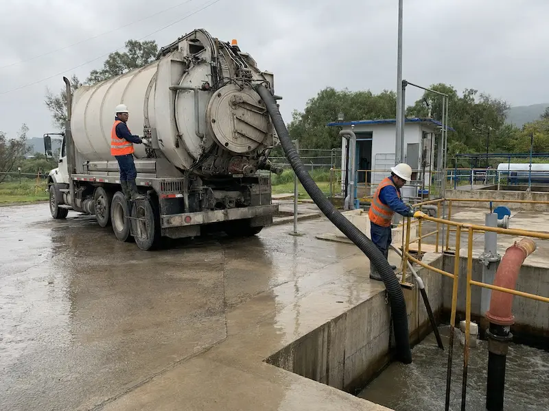 Camión vactor de 17 m³ estacionado junto a un cárcamo de bombeo con la manguera de succión tendida