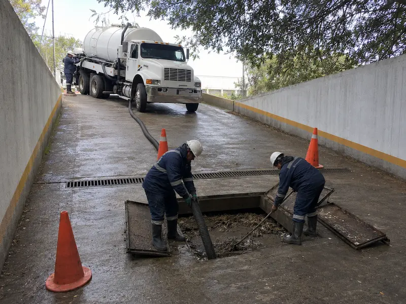 Pozo de visita abierto con equipo de desazolve en una vialidad interna en Querétaro